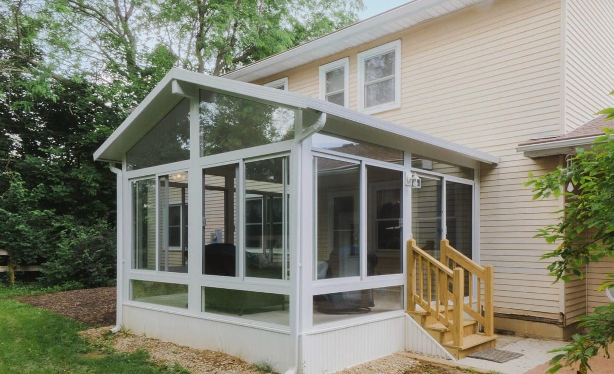 Three-season sunroom addition with white frame attached to residential home